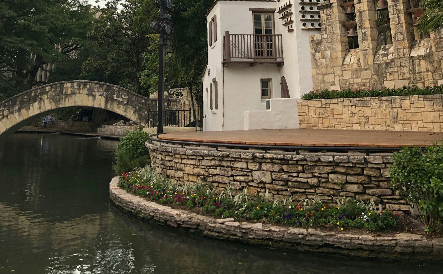 The San Antonio River Walk: a stone footbridge and a white building beside the river
